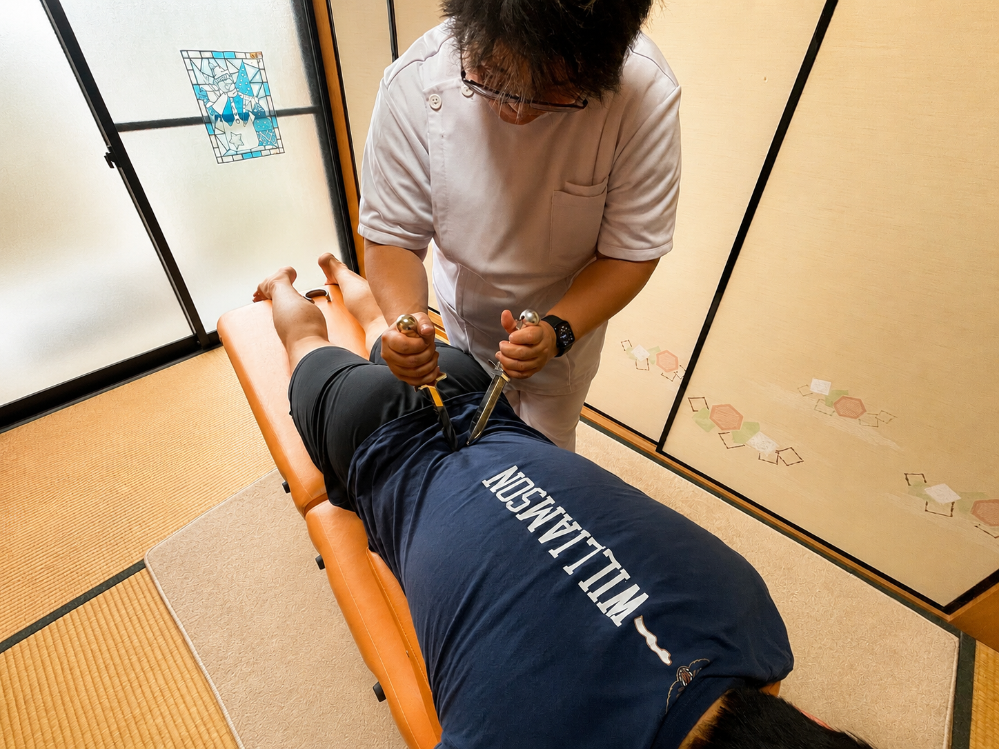 玄関先で出張施術の準備を整えたバッグと折りたたみベッド